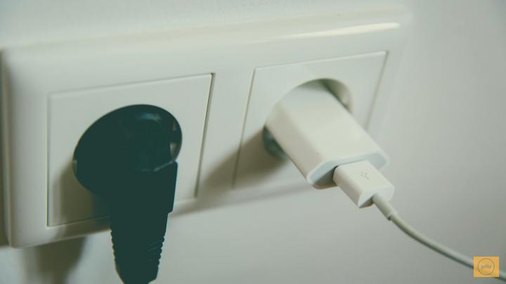 Two plugs in a white electrical outlet, one black and one white.